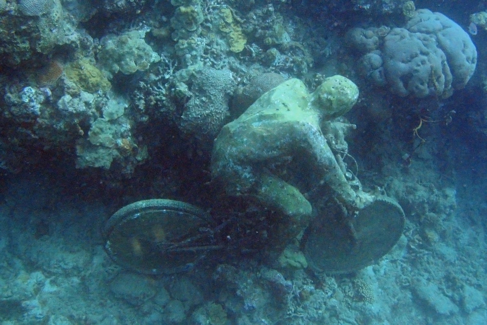 The Fall from Grace, a cyclist figure sculpture beside the reef in Molinière Bay